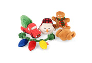 Play Merry Minis Collection, a set of five plush Christmas-themed dog toys on a white background: a red truck carrying a green Christmas tree, a snowman wearing a red plaid hat, a gingerbread man with a red and green scarf, a brown turkey plush dog lying on its side, and a string of colorful toy Christmas lights in front.
