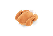 Play Merry Minis Holiday Hound Turkey plush toy shaped like a roasted turkey, made of soft tan-brown fabric with small white accents for the beak and legs, shown on a plain white background.