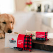 Load image into Gallery viewer, A golden retriever looks at the Cabot Creamery Vermont Seriously Sharp cheddar cheese bar and matching Cabot Creamery x Play Seriously Sharp dog toy on a wooden cutting board in a bright kitchen.
