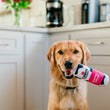 Load image into Gallery viewer, Dog holding a Cabot Creamery x Play Whipped Cream Crinkler dog toy in its mouth in a kitchen setting
