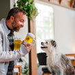 Load image into Gallery viewer, P.L.A.Y. Hollywoof Cinema Hoppy Hound Brew Toy - dog dad smiling at dog with real beer and toy handing it to scruffy white dog smiling up at him
