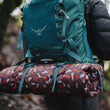 Load image into Gallery viewer, Scout &amp; About Outdoor Chill Pad in Mocha strapped onto a hiking backpack being worn by a hiker
