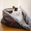 Load image into Gallery viewer, P.L.A.Y. Snuggle Bed - Husky Gray with white and black cat stretching out inside
