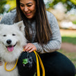 Load image into Gallery viewer, Proper Pup Poop Bag Dispensers from P.L.A.Y. - Kalahari Black on yellow leash being held by human as she smiles at her fluffy white dog also smiling
